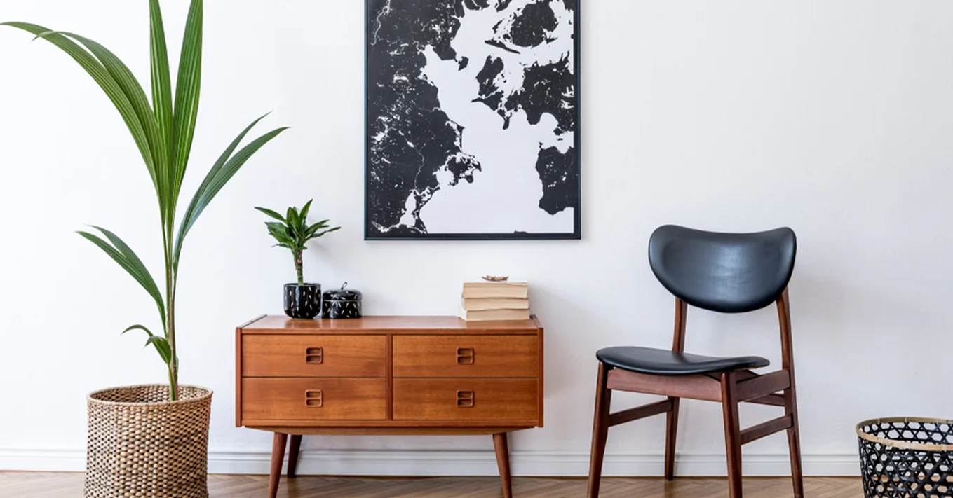 Sterling Developers Minimalist interior with wooden furniture, a black chair, and potted plants.